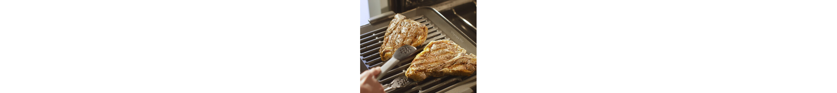 A hand flipping chicken on a grill pan with silver tongs