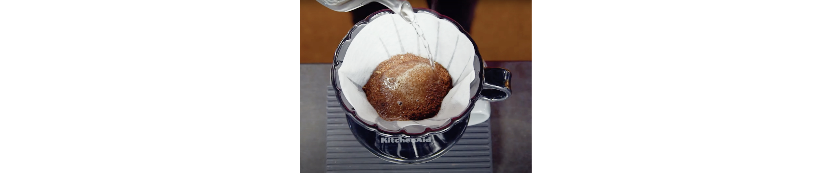 Top view of boiled water being added to coffee grounds in pour over filter