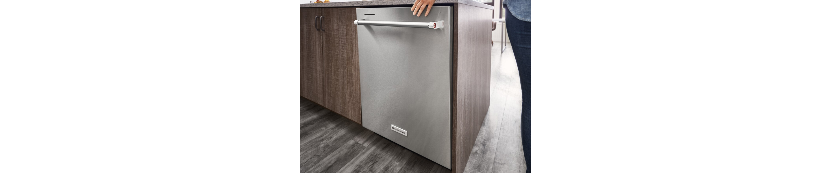 A hand closing a stainless steel dishwasher