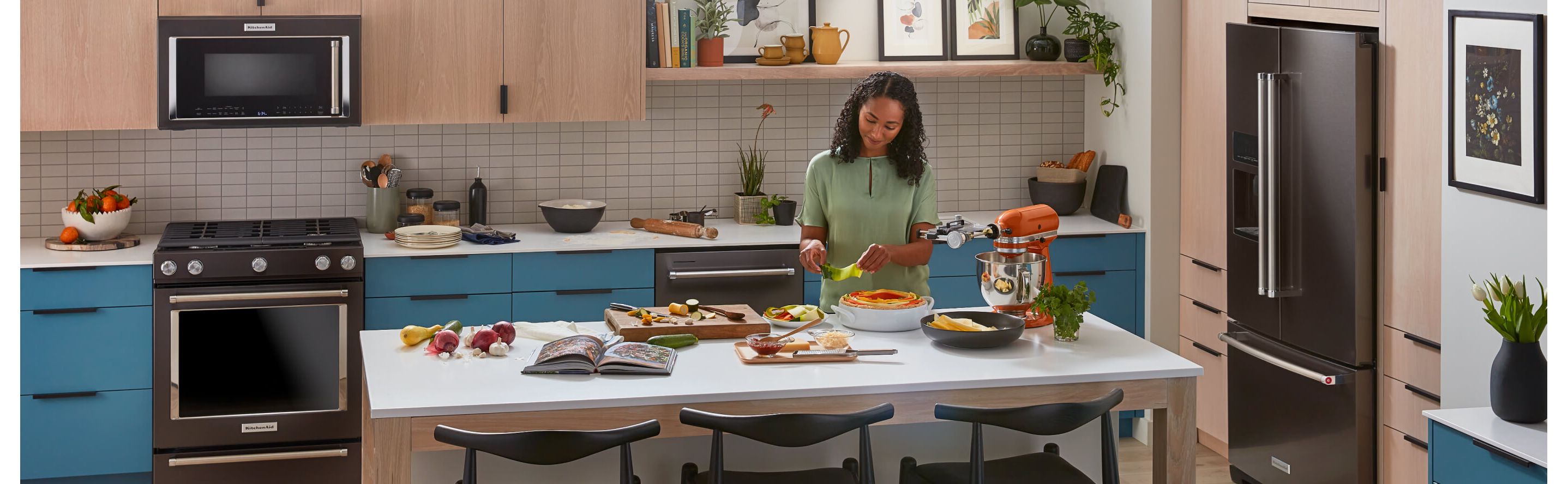 Person preparing food in a kitchen with KitchenAid® appliance suite
