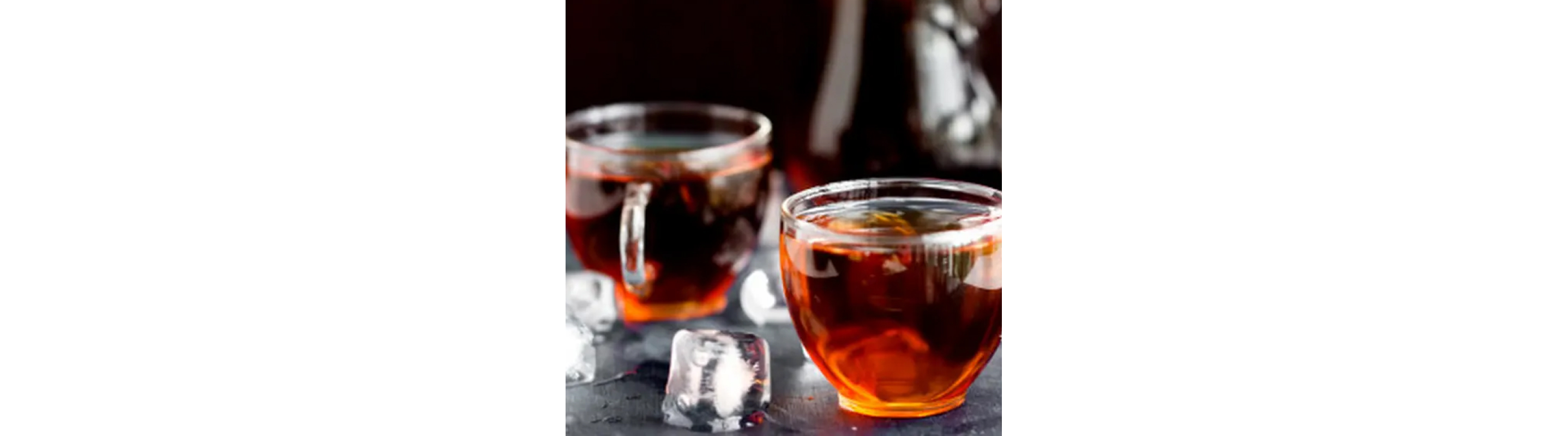 Two glass mugs of tea next to ice cubes