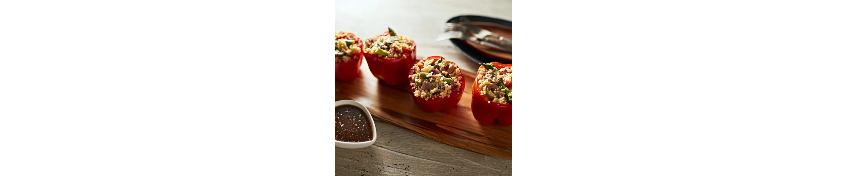 Stuffed red peppers on a wood serving board.