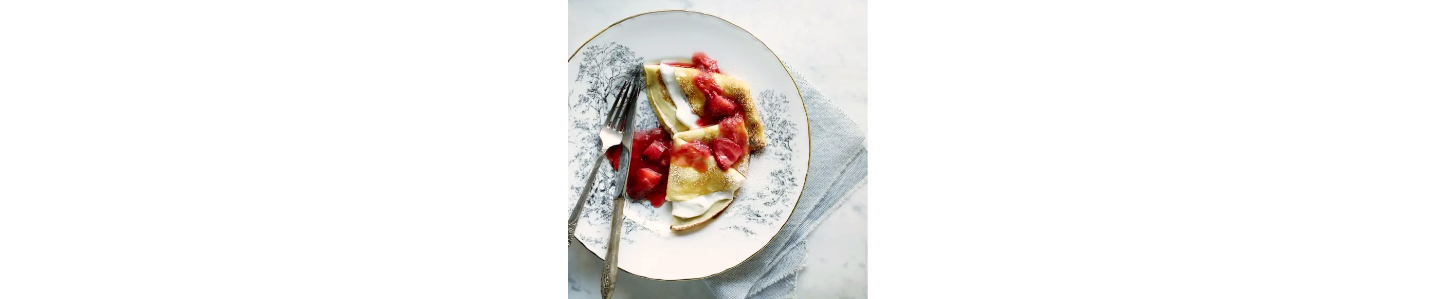 Delicate crepes with strawberries and rhubarb on top.