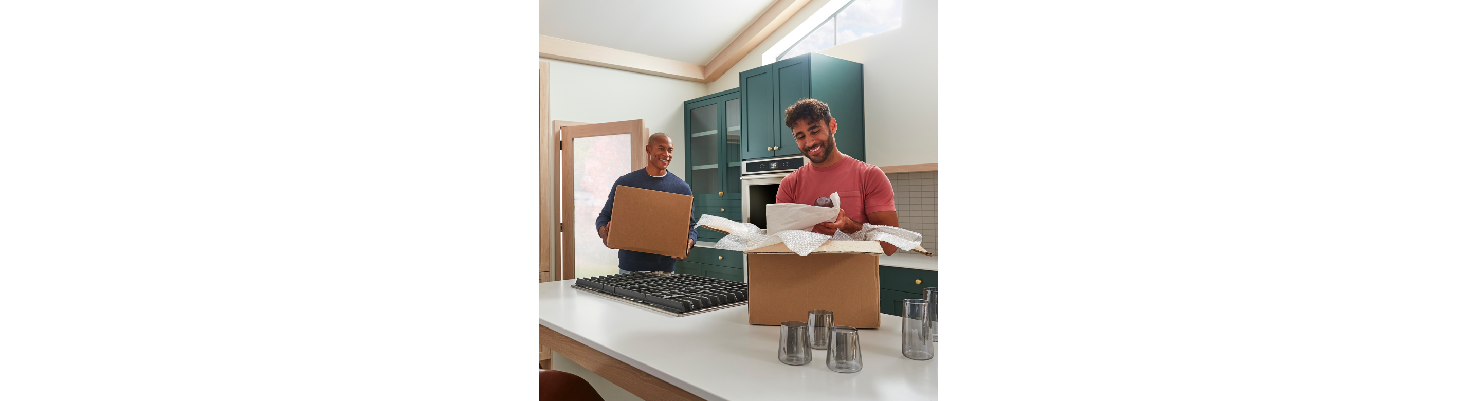 Two men moving and unpacking boxes in a remodeled kitchen.