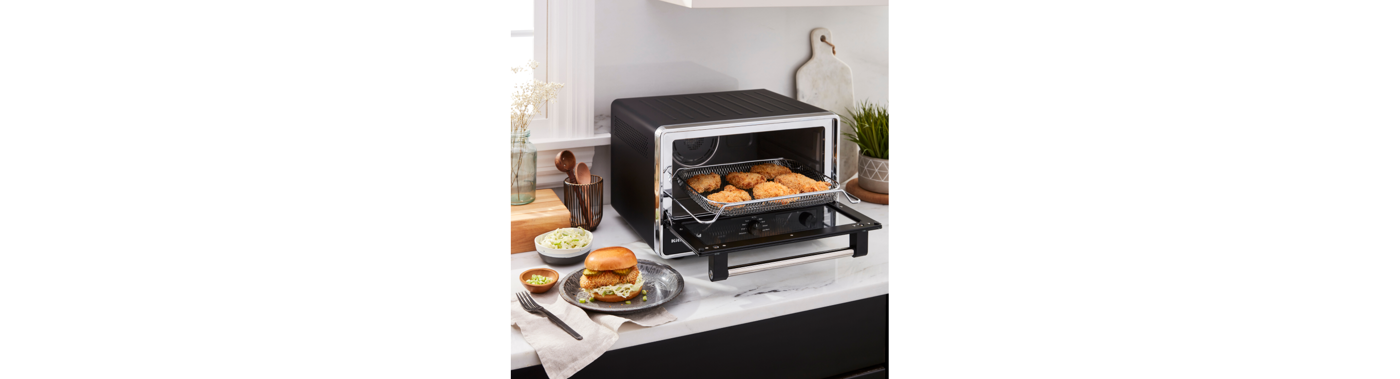 A KitchenAid® countertop oven preparing chicken patties for sandwiches.