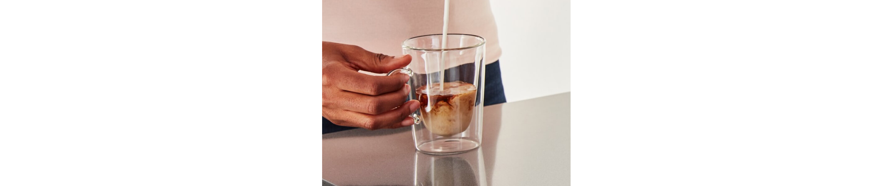 Close-up of person pouring milk into espresso cup