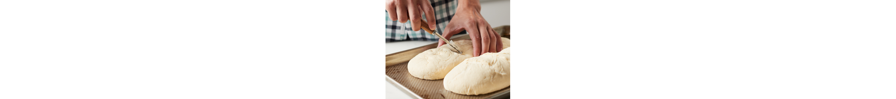 A man scoring raw bread loaves