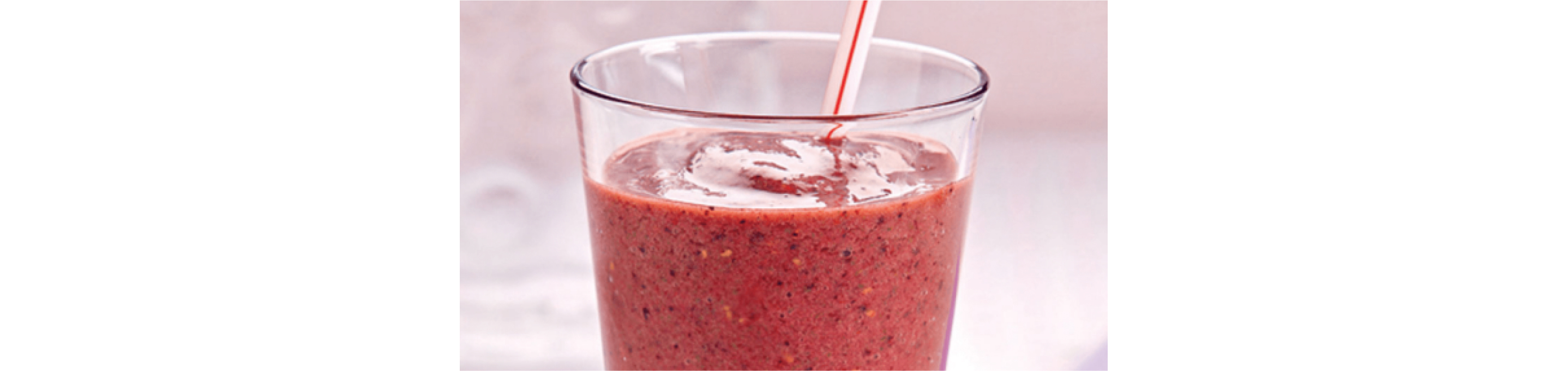 A red fruit smoothie in a glass.