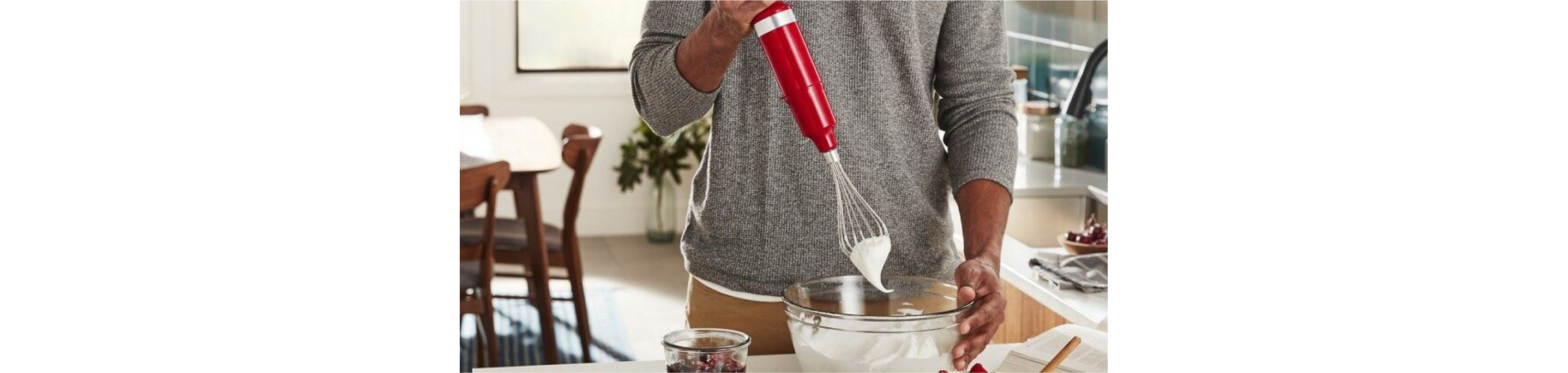 A peson using a hand blender to whip cream.