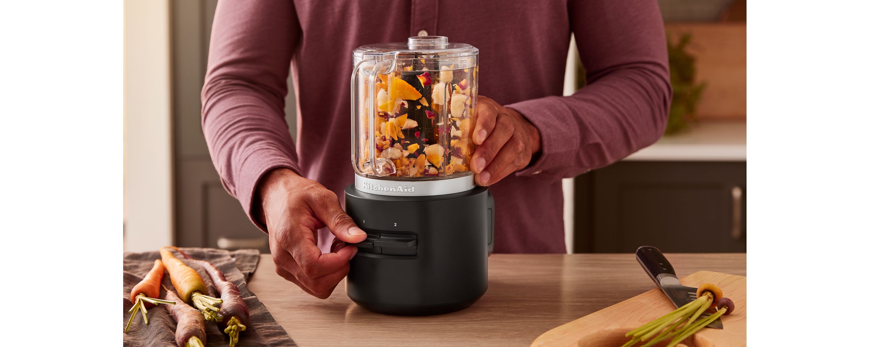 A person operating the KitchenAid Go™ Cordless Food Chopper with vegetables inside.