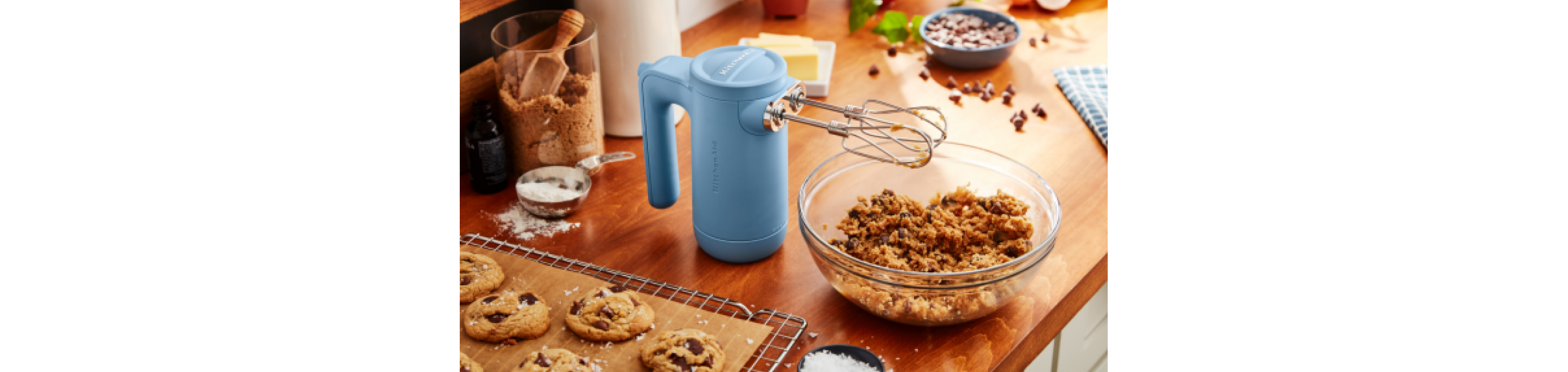 A Blue Velvet Cordless Hand Mixer standing upright over a bowl of cookie dough.