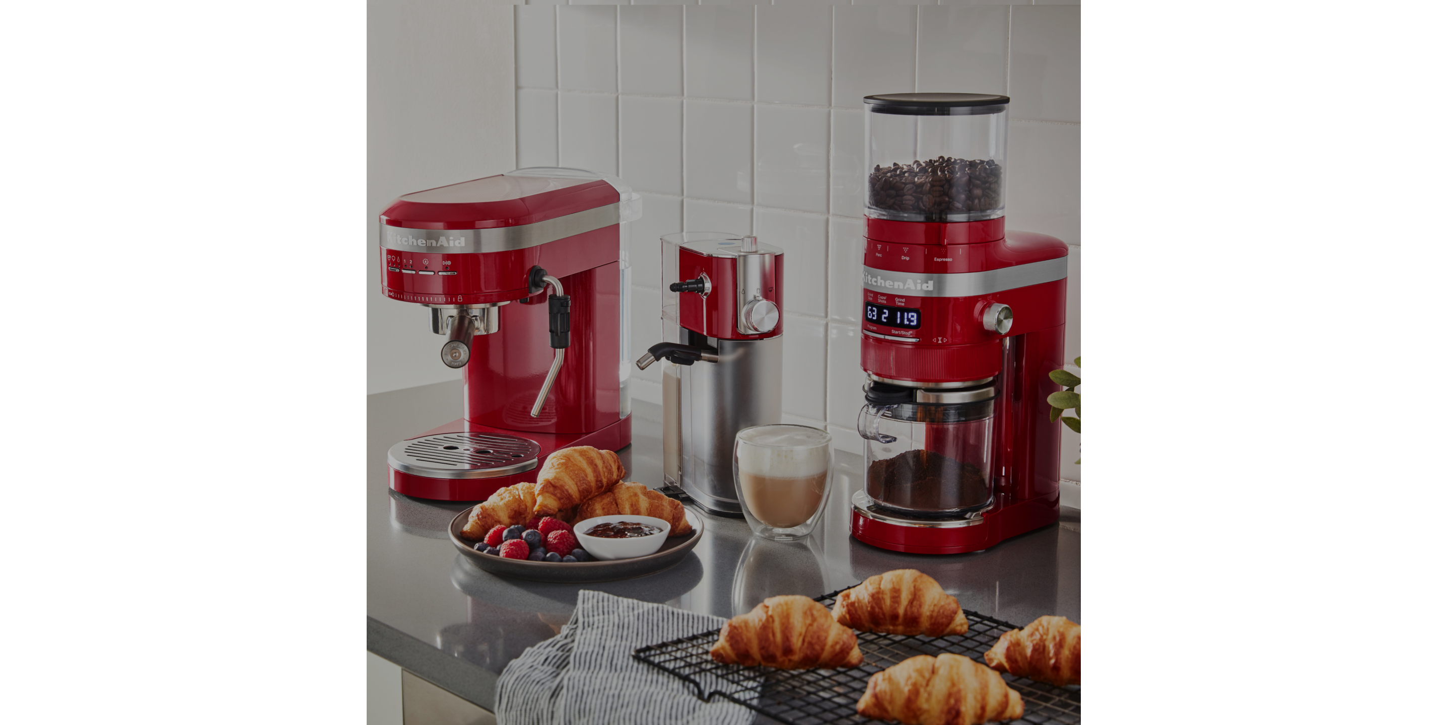 A close-up of a kitchen countertop with two red KitchenAid® countertop appliances.