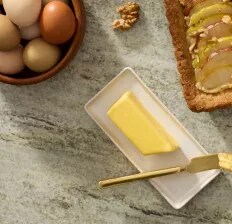 A stick of butter on a butter plate with a brass spreader