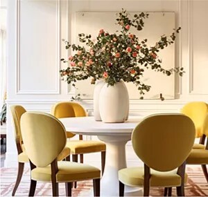 A flower arrangement on a dining room table with pale yellow upholstered dining chairs