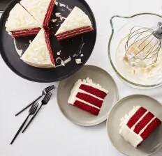A sliced red velvet cake on a black serving tray