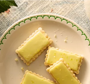 Four shortbread cookies glazed in a pale yellow yuzu glaze.