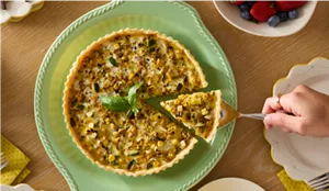 A person taking a slice of a quiche.