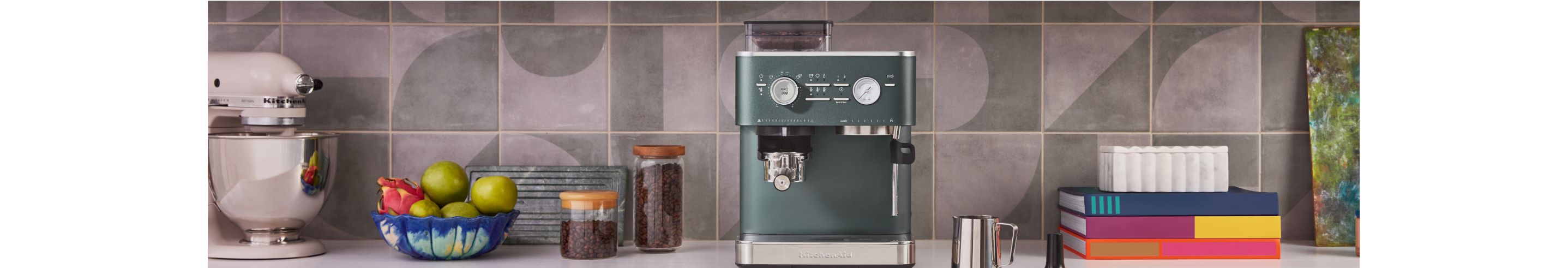 A KitchenAid® espresso machine in juniper, with a person tamping down espresso grounds.