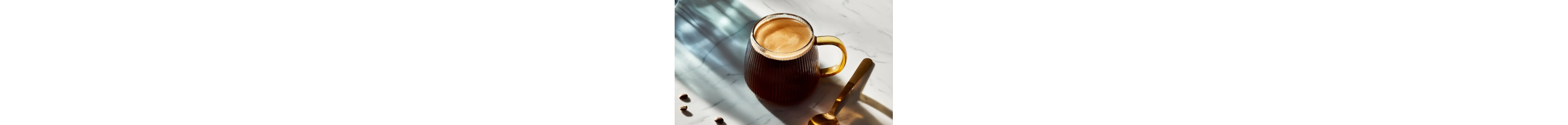 Americano in a glass mug next to a gold spoon