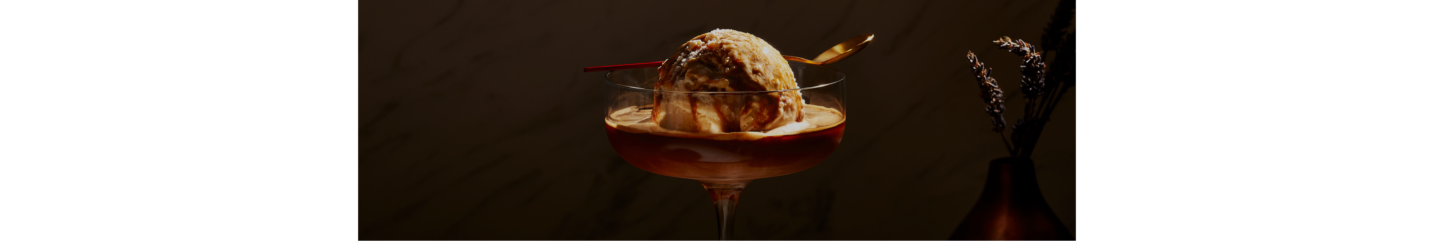 A close up image of a large scoop of vanilla ice cream with a shot of espresso poured over.