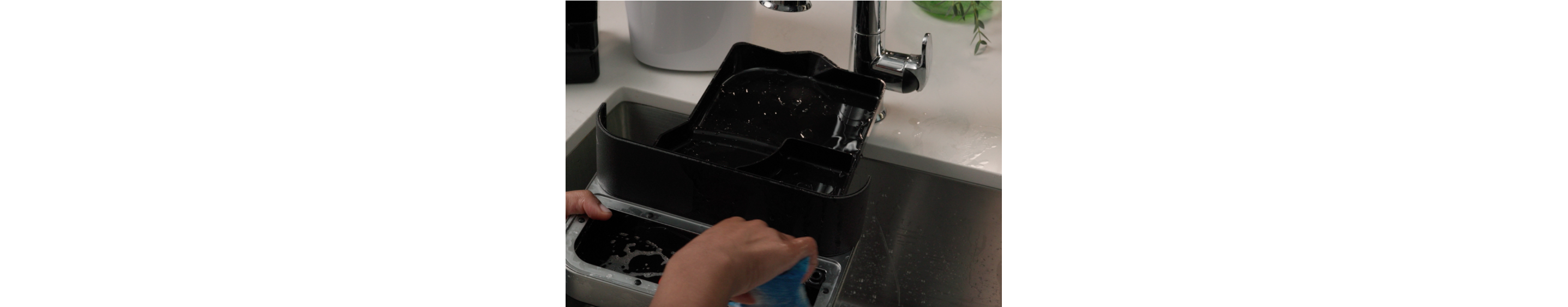 Person cleaning an espresso machine drip tray