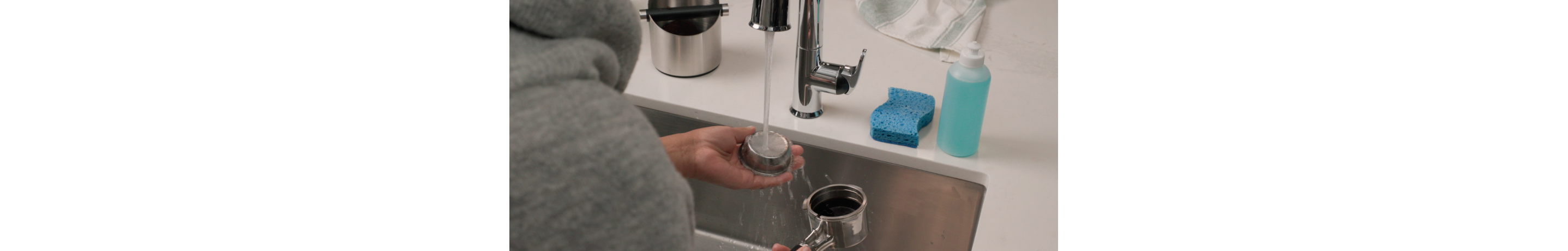 Person rinsing an espresso portafilter in the sink