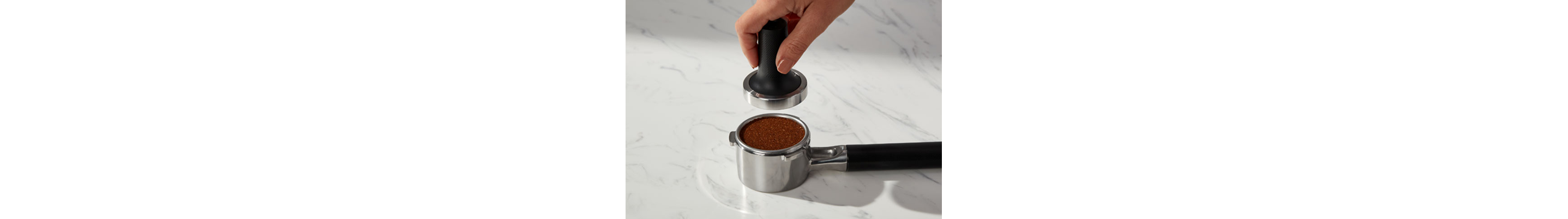 Hand tamping down espresso inside a portafilter
