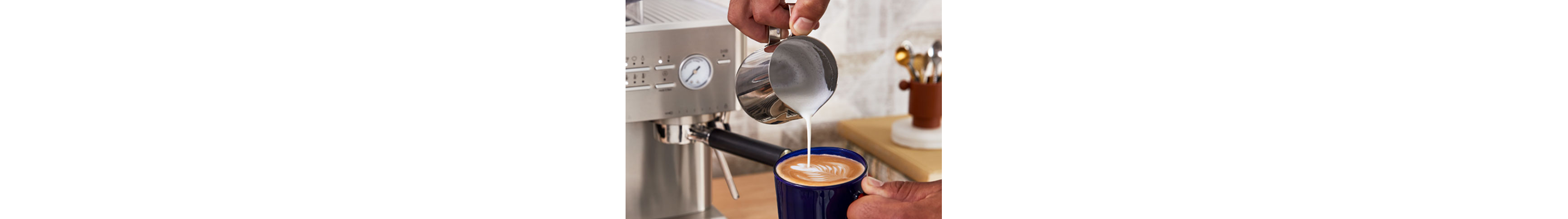 Hand making latte art from milk pouring out of the milk pitcher