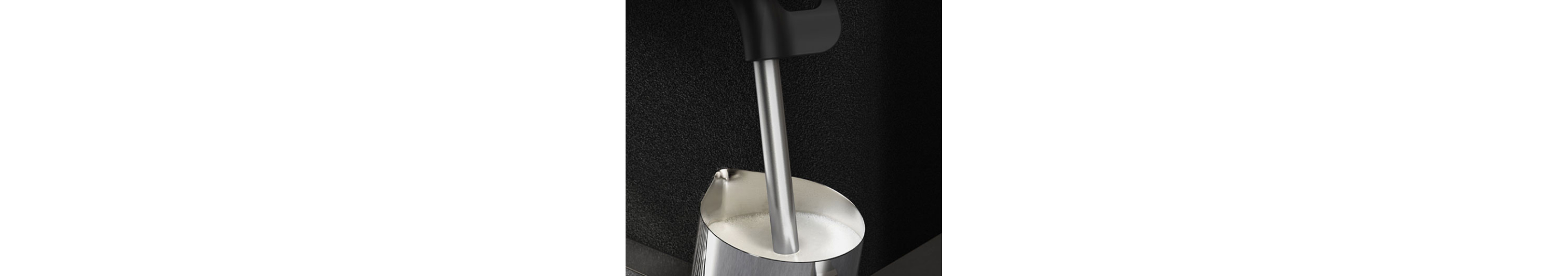 A steam wand inside a cup of milk