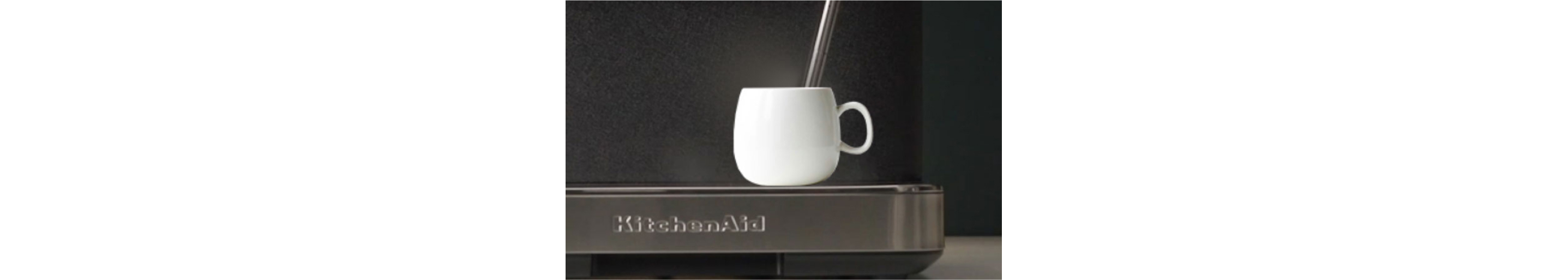 An espresso cup on a KitchenAid® Espresso Machine with a steam wand inside of it