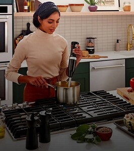 A person making soup on a KitchenAid® cooktop