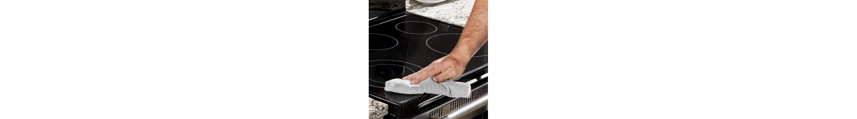 Hand using a dry towel to polish an induction cooktop