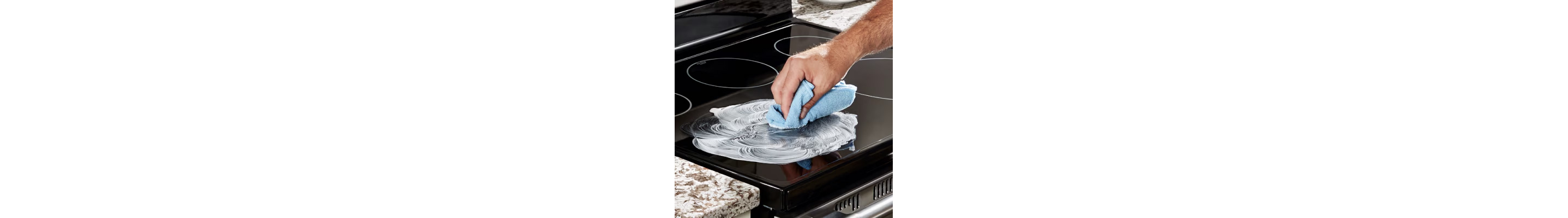 Hand wiping an induction cooktop with a towel