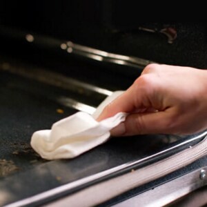 Person wiping down the interior of an oven
