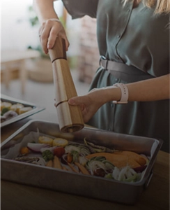 A person seasoning a dish.