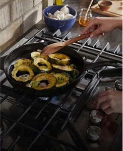 A person cooking vegetables on a cooktop.