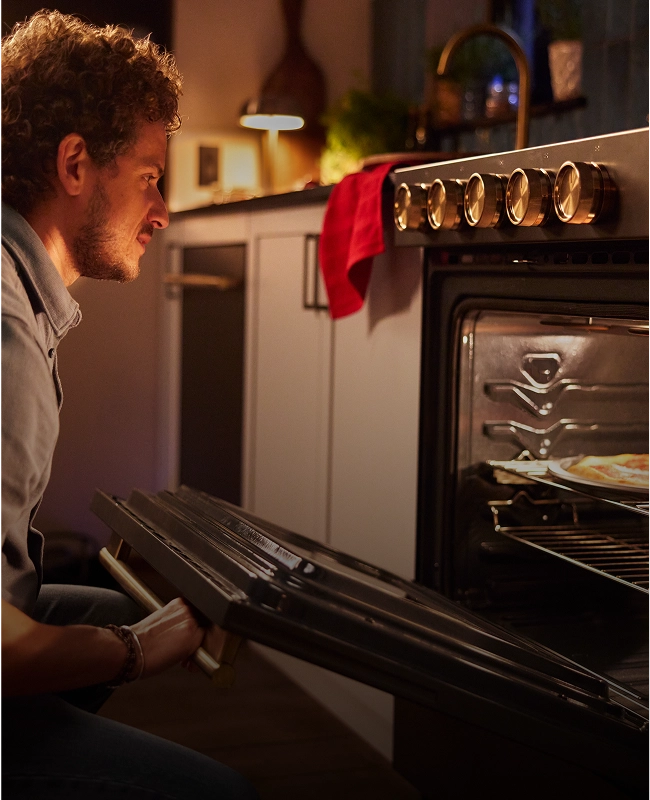 A person about to pull a dish out of the oven.