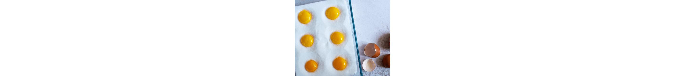 Egg yolks in a glass dish filled with salt