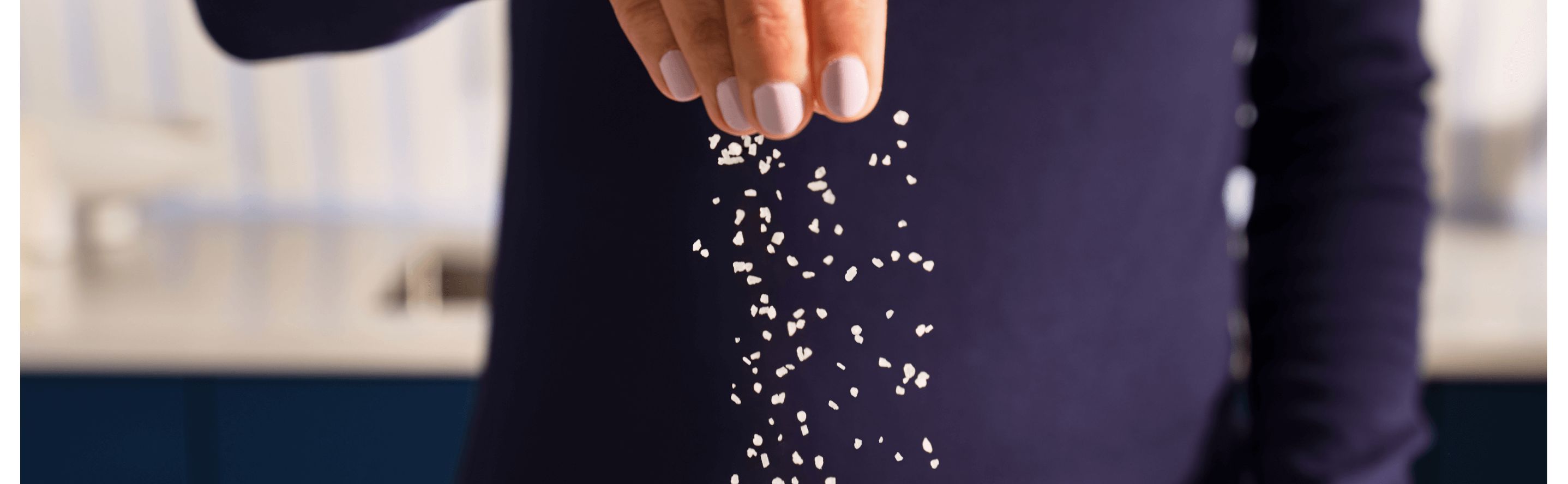 Person in a dark blue sweater sprinkling salt
