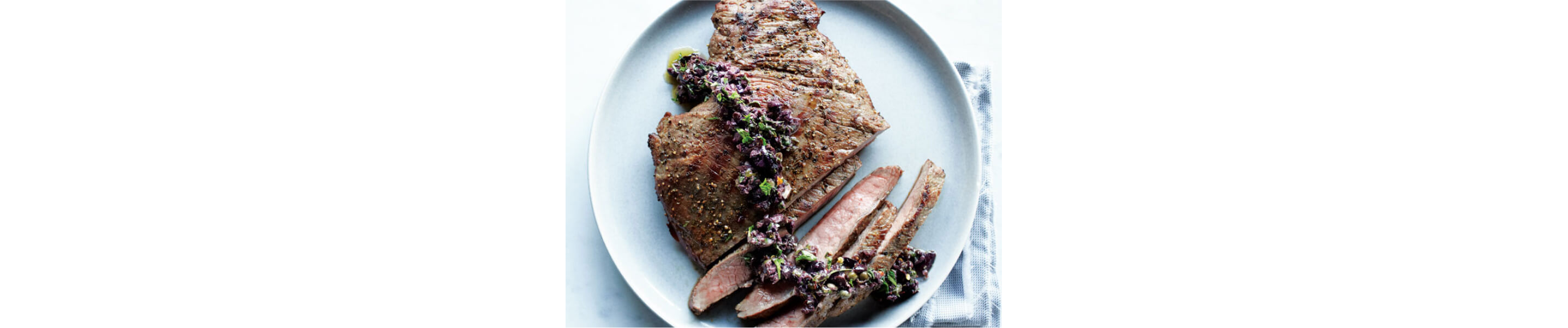 Sliced flank steak with a bright sauce on top
