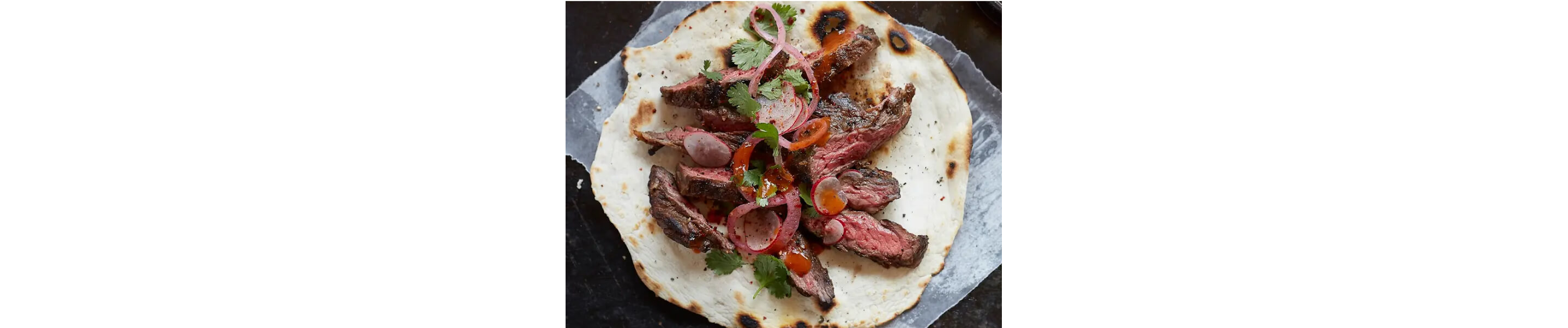 Skirt steak inside a tortilla with pickled onions