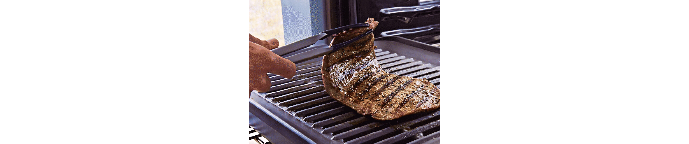 Person cooking a strip steak on their KitchenAid® smart oven grill attachment