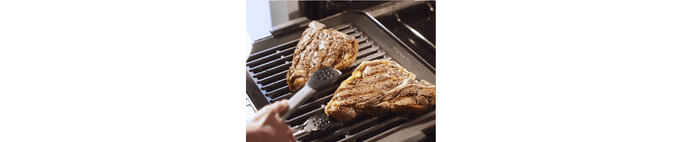 Person grilling a t-bone steak in their KitchenAid® smart oven