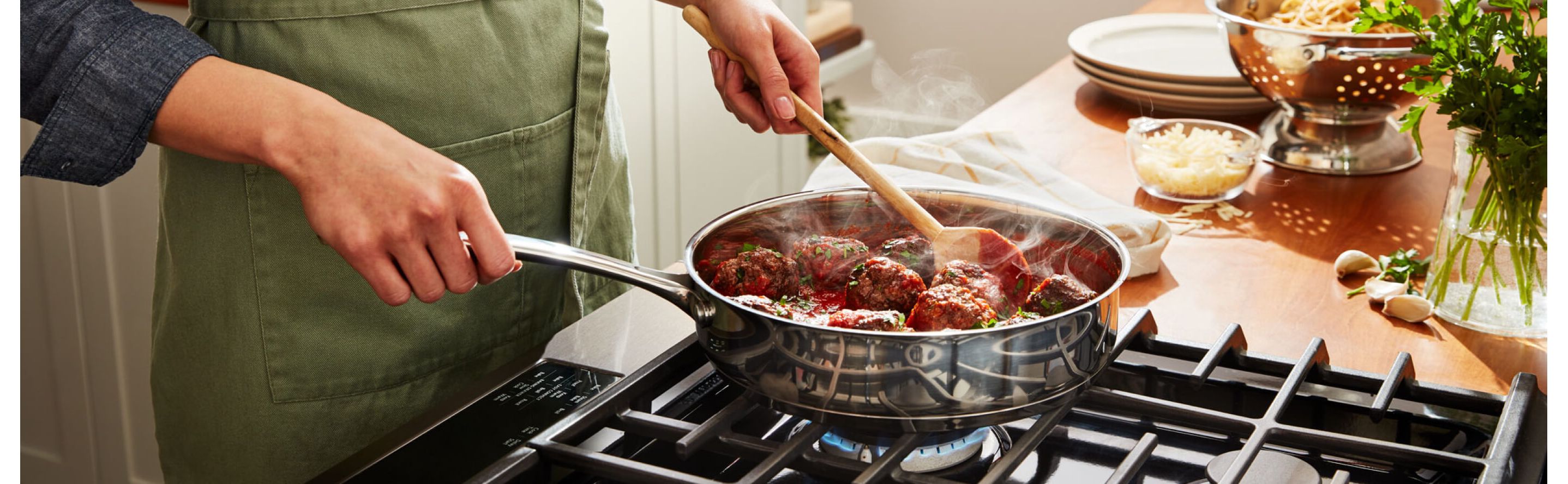 A person preparing food in a pan on a gas cooktop