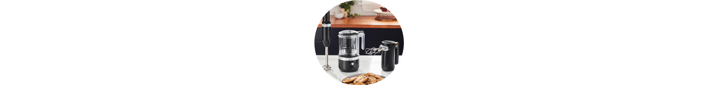Matte Black KitchenAid® cordless immersion blender, food chopper, and hand mixer on white countertop.