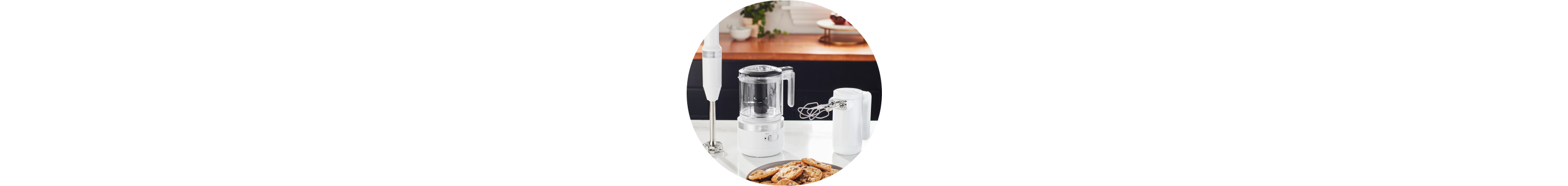 White KitchenAid® Cordless Immersion Blender, Food Chopper, and Hand Mixer on white countertop.