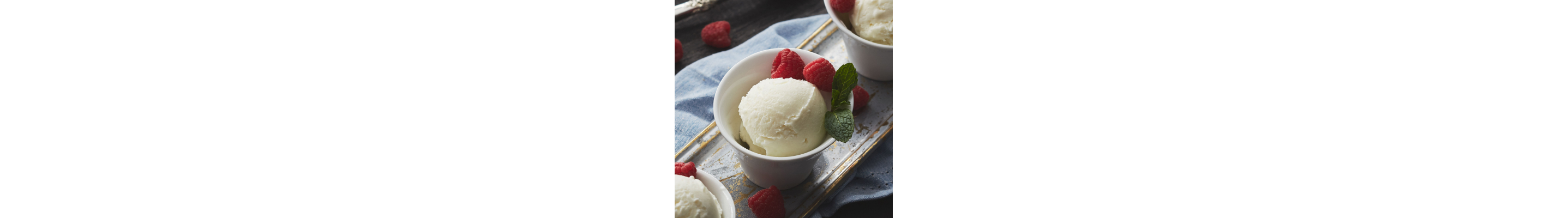 Individual bowls with scoops of vanilla ice cream and fresh raspberries on a table