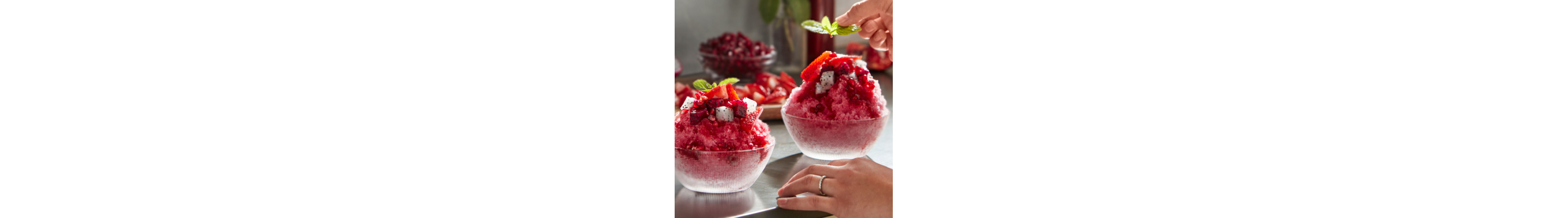 Shaved ice dessert garnished with fruit and mint