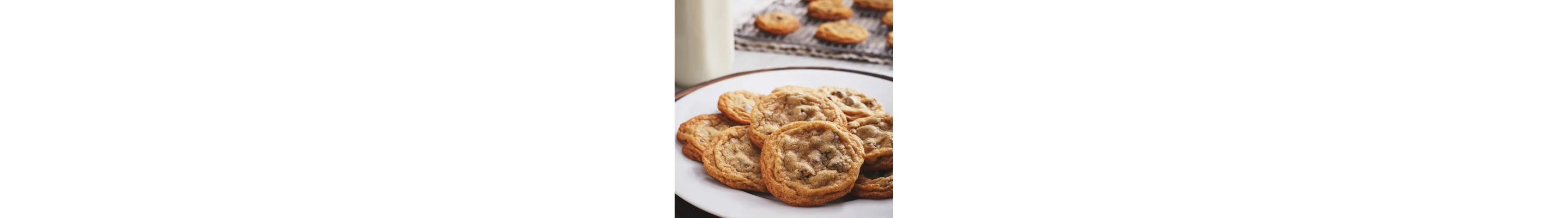 Baked chocolate chip cookies on a plate next to a cooling rack