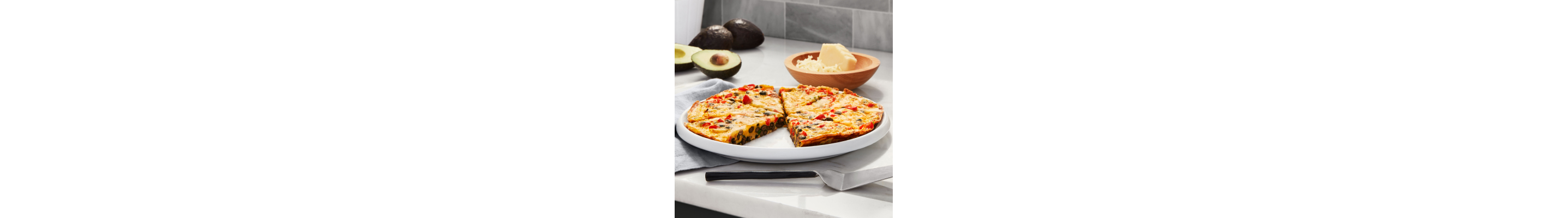 Plate of quiche on countertop with cheese and avocado